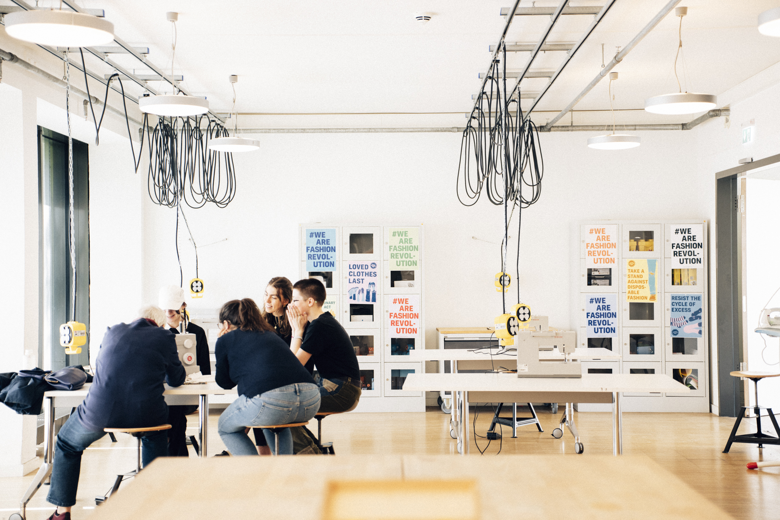 People working in a sewing and clothing repair workshop in a space dedicated to sustainable fashion.